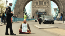 Man sitting in in the middle of bridge protesting for climate action