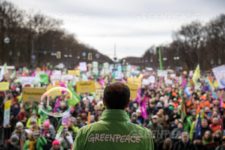 Greenpeace activist standing in front of a huge crowd of people supporting him