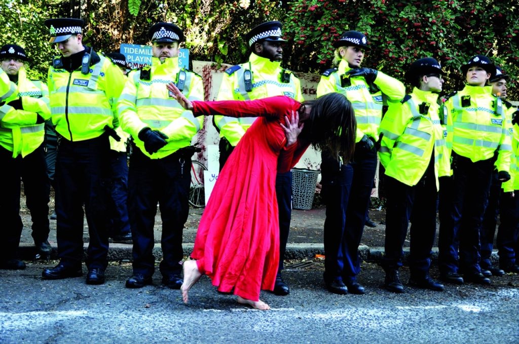 Woman in a beautiful red dress dancing in front to policeman