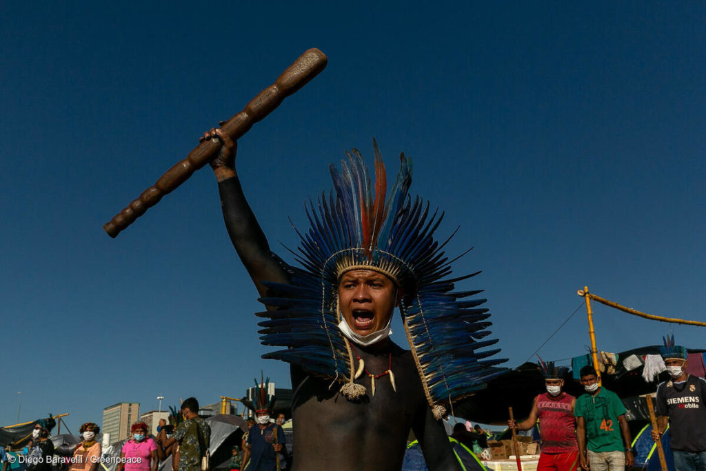 Indigenous man decorated with feathers fghting in a protest