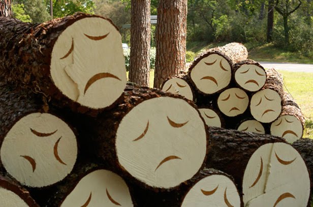 Cut down trees with sad faces painted on their logo